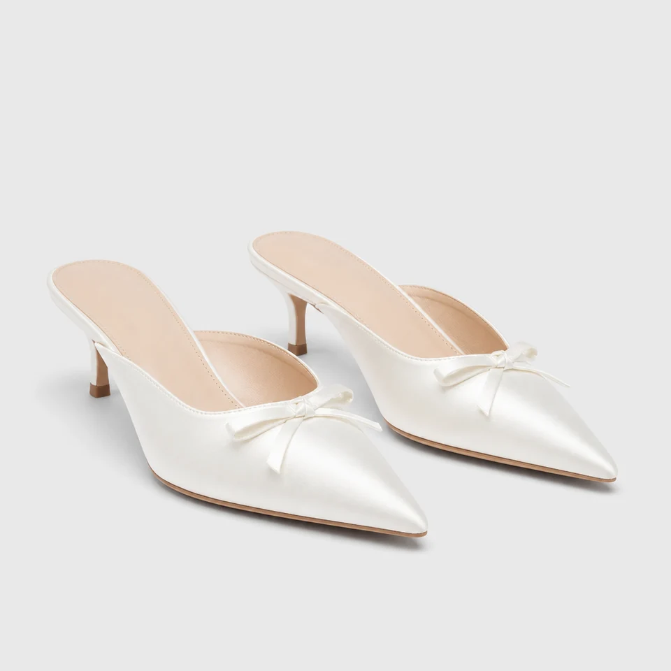 Pointed white satin-look kitten heel mules with open back and bow detail